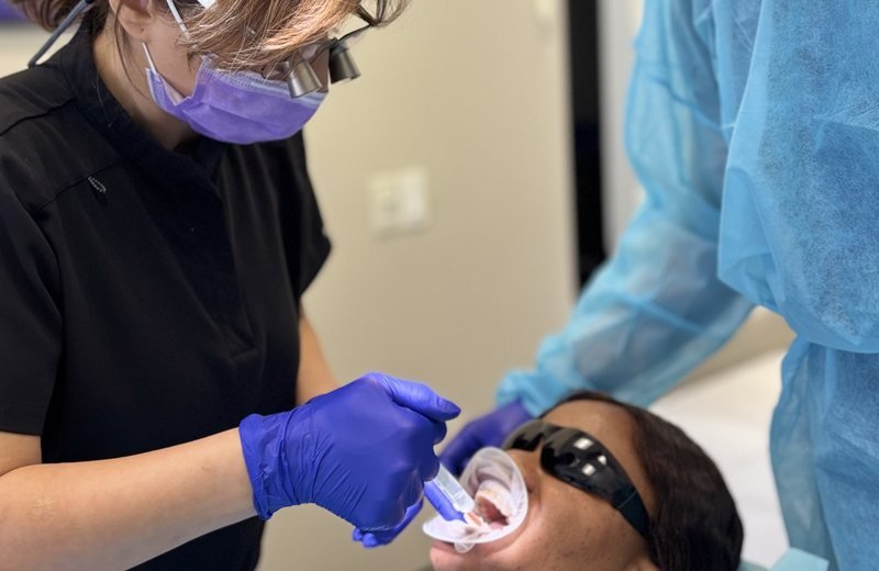 Dentist performing professional teeth whitening treatment at Hola Dentistry in Bradford